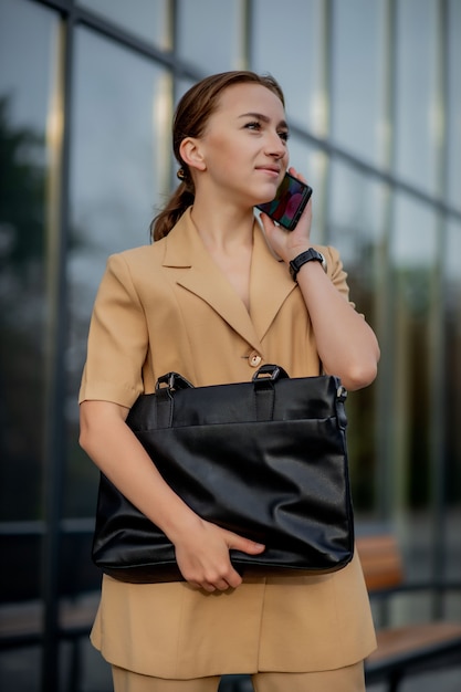 Portrait of an young successful businesswoman is smiling satisfied with her work in camera near office.