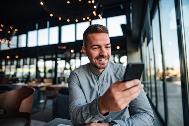 Portrait of young successful entrepreneur using smartphone.