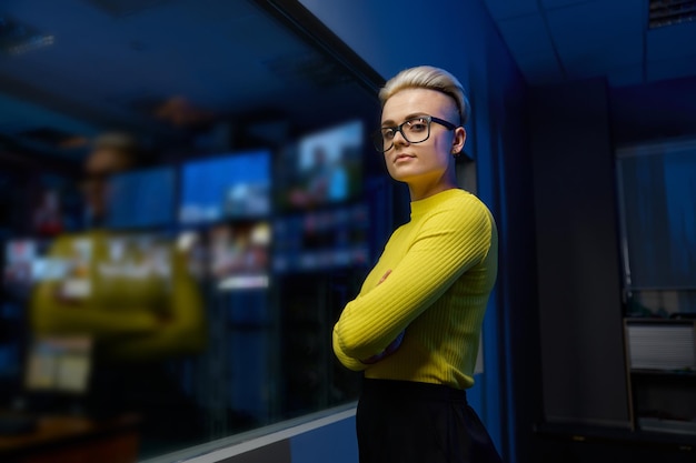 Портрет молодой и успешной работницы центра обработки данных, смотрящей на камеру, стоящую в темной серверной комнате