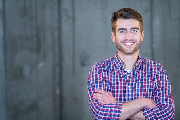 portrait of young successful smiling casual businessman standing in front of a concrete wall at new startup office