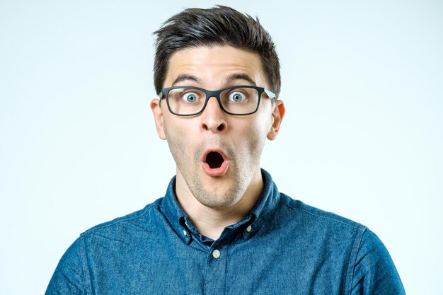 Portrait of young surprised man with opened mouth Isolated on gray