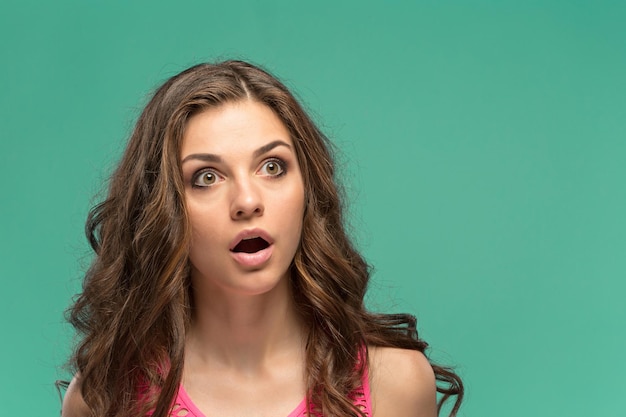 The portrait of young surprised woman with shocked facial expression
