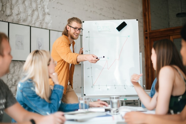 Portrait of young teacher standing near board and happily 