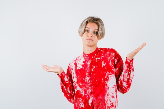 Portrait of young teen boy showing helpless gesture in shirt and looking confused front view