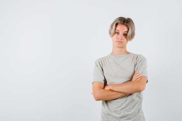 Tシャツを着て腕を組んで立って自信を持って正面を見て立っている若い10代の少年の肖像画