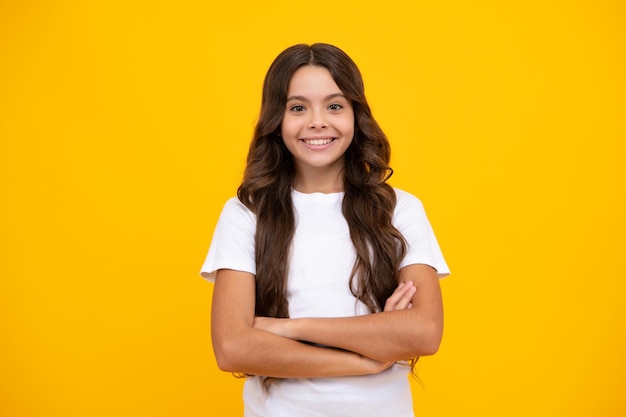 Portrait of young teenage girl standing with crossed arms against yellow background with copy space