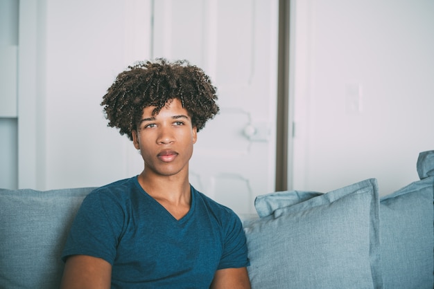 Photo portrait of a young thoughtful mixed race man sitting in the sofa