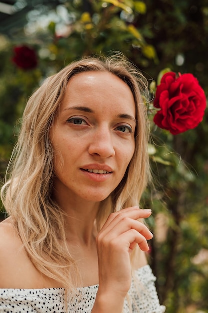 Portrait of a young tired woman near red roses