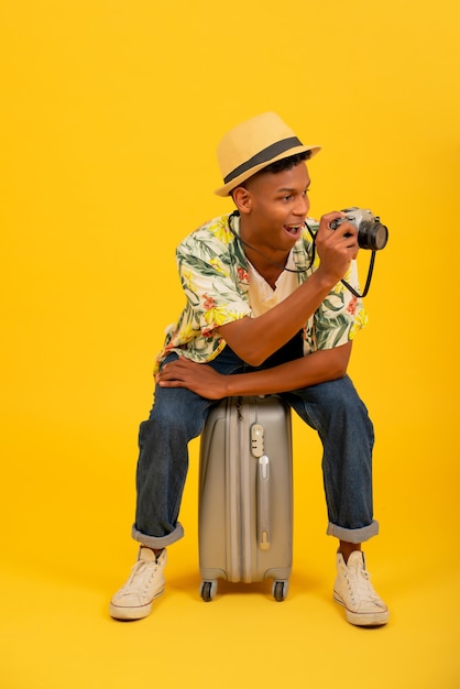 Portrait of a young tourist man taking photos with a camera over isolated background. Travel concept.