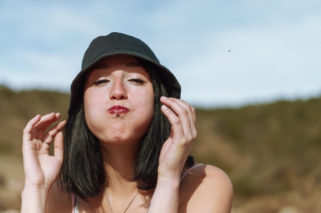 Portrait of young tourist woman on the mountain looking at the camera with inflated cheeks