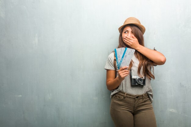 Photo portrait of young traveler latin woman against a wall covering mouth, symbol of silence and repression