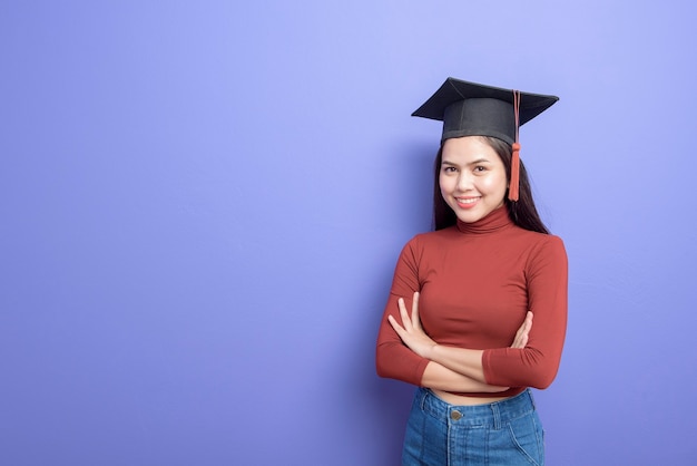 Portrait of young University student woman with graduation cap on violet