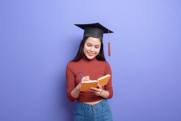 Portrait of young University student woman with graduation cap on violet