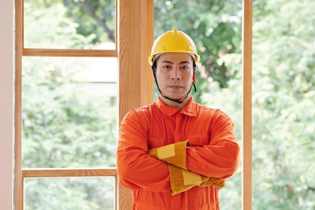 Portrait of young vietnamese foreman standing with arms crossed in front of freshly installed big wi...