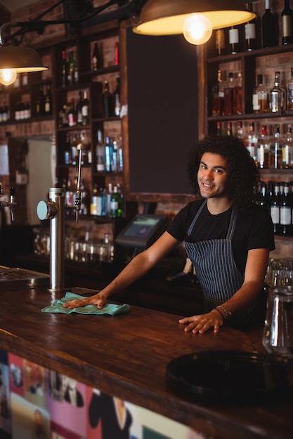 Portrait of young waiter cleaning a counter