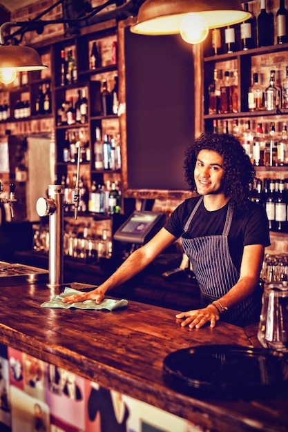 Portrait of young waiter cleaning a counter