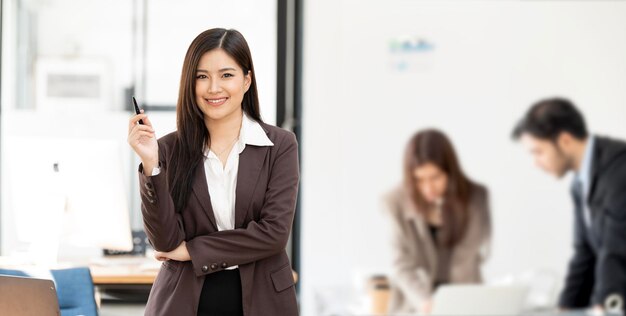 Portrait of young white woman in a busy modern workplace smiling to camera