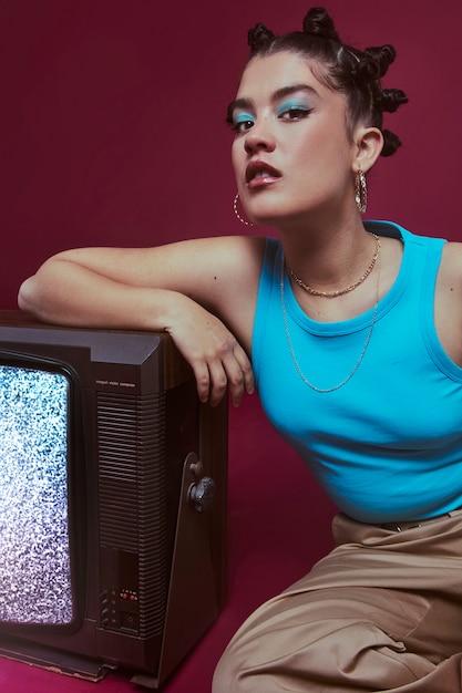 Foto ritratto di giovane donna in stile moda anni 2000 in posa con la tv