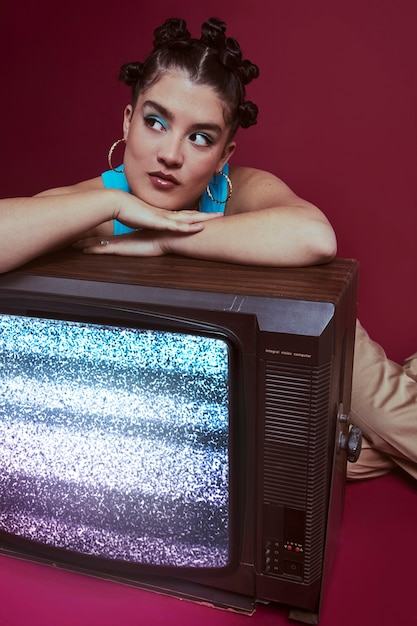 Portrait of young woman in 2000s fashion style posing with tv