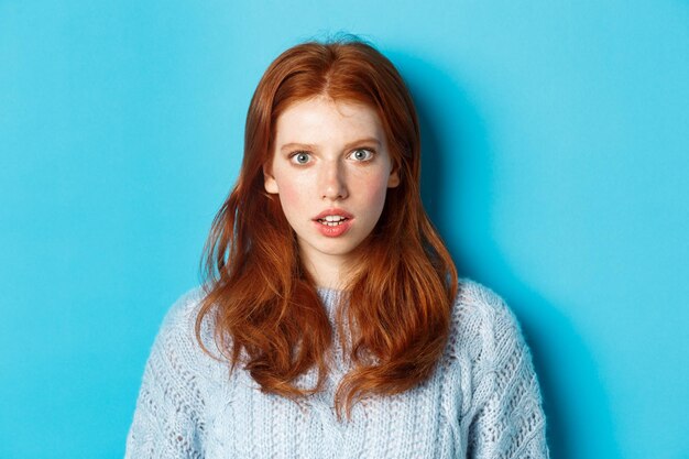 Portrait of young woman against blue background