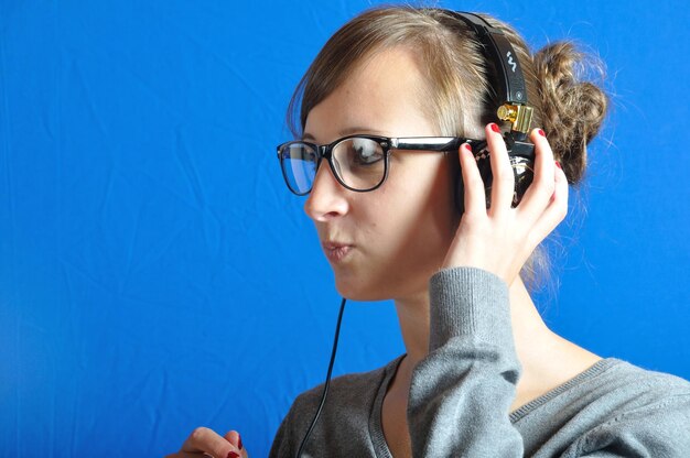 Portrait of young woman against blue wall