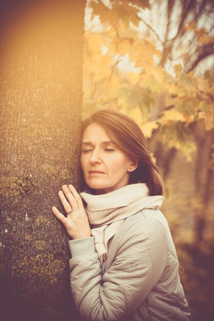 Portrait of young woman against tree trunk