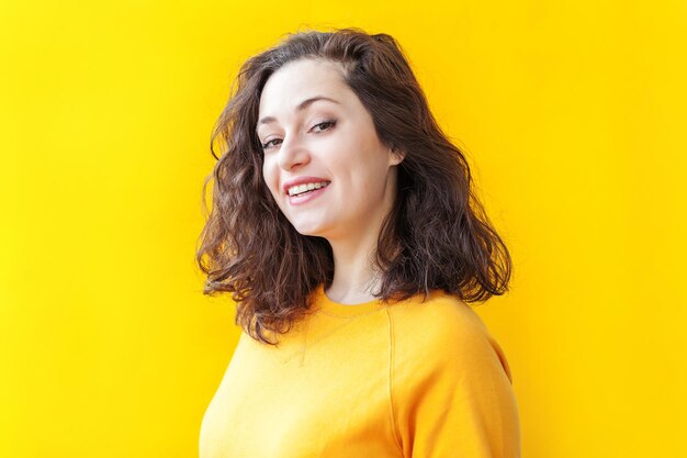 Portrait of young woman against yellow background