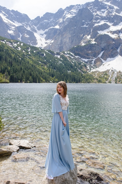 Portrait of a young woman on the background of the Polish lake "Sea Eye" in the Tatra Mountains. Portrait photography in the background of a quiet place without people.