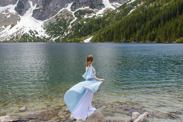 Portrait of a young woman on the background of the Polish lake "Sea Eye" in the Tatra Mountains. Portrait photography in the background of a quiet place without people.