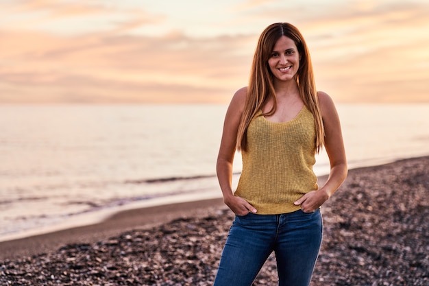 Foto ritratto di una giovane donna sulla spiaggia al tramonto