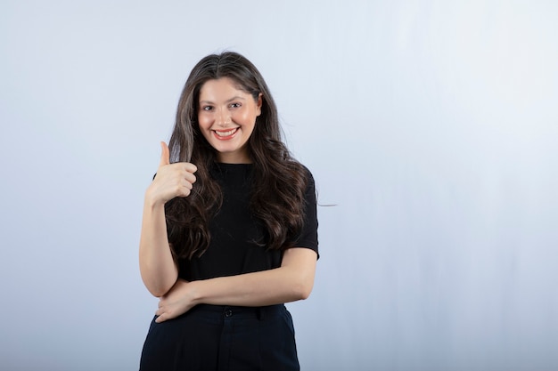 Portrait of young woman in black outfit giving thumbs up. 