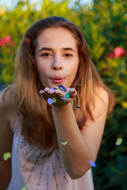 Foto ritratto di una giovane donna che soffia confetti