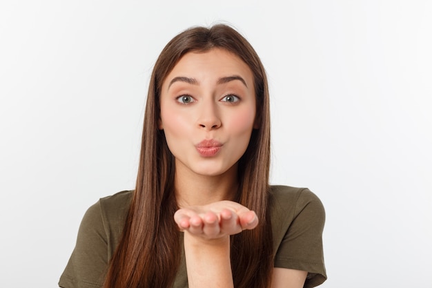 Portrait of a young woman blowing a kiss isolated over white.