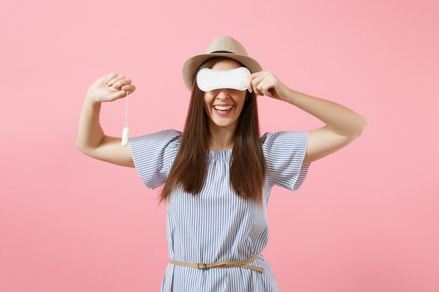 Portrait of young woman in blue dress holding sanitary napkin, tampon for variant safety menstruation days isolated on pink background. Medical healthcare, gynecological, choice concept. Copy space.