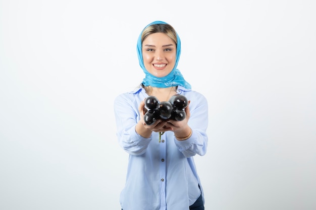 Portrait of young woman in blue shawl holding uncooked eggplants