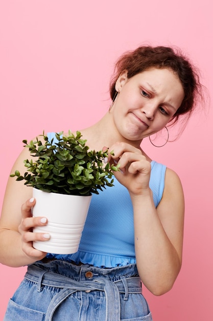 Portrait of a young woman in a blue Tshirt and shorts a flowerpot isolated backgrounds unaltered