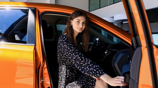 Portrait of a young woman in a car buying a new car at a dealership