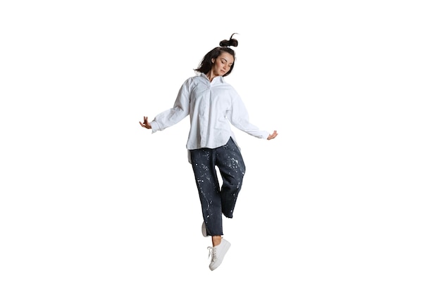 Portrait of young woman in casual cloth making dance moves isolated over white background