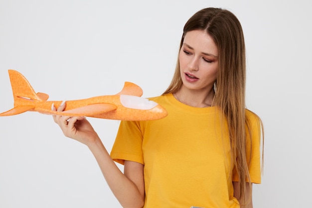 Portrait of a young woman in casual clothes an airplane in his hands isolated background