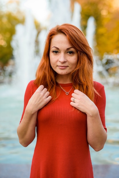 Portrait of young woman in casual wear posing near fountain outdoors