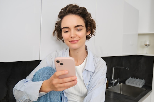 Portrait of young woman checking her mobile phone reading message on smartphone and smiling