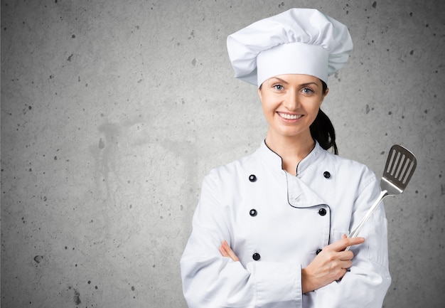 Portrait of young woman chef on background