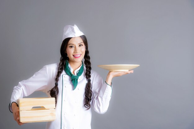 Portrait of young woman chef isolated on Gray background