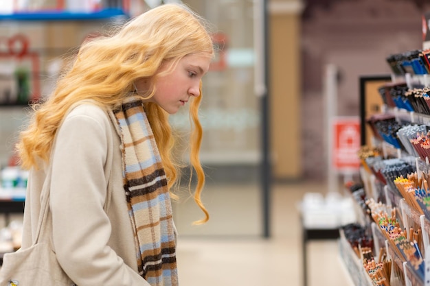 Portrait of young woman choosing school stationery in\
specialized store