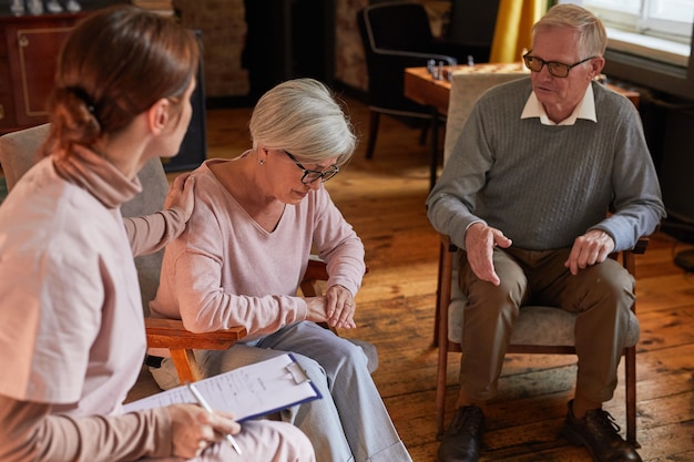 Portrait of young woman comforting senior lady during therapy session at retirement home, copy space