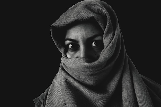 Photo portrait of young woman covering face against black background