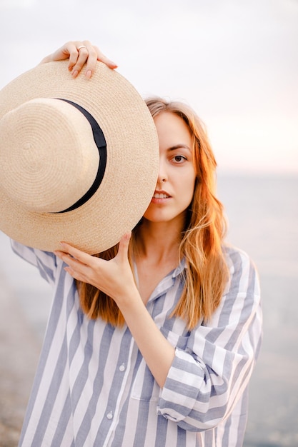 海を背景に帽子で顔を覆う若い女性の肖像画