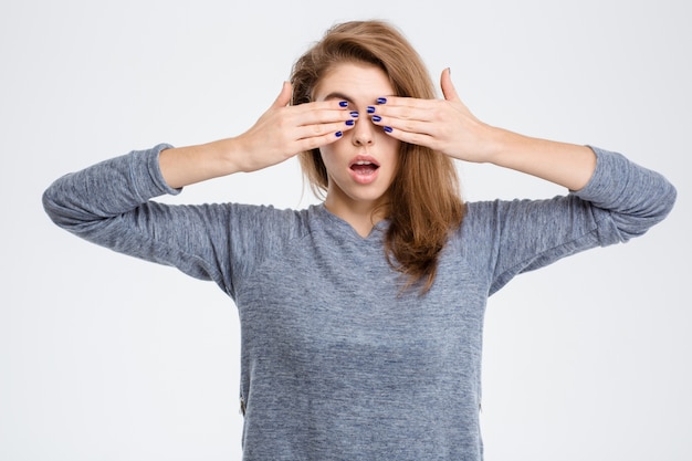 Portrait of a young woman covering her eyes with palms isolated on a white background