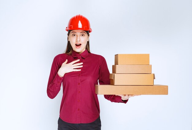 Portrait of a young woman in crash helmet holding paper boxes . 