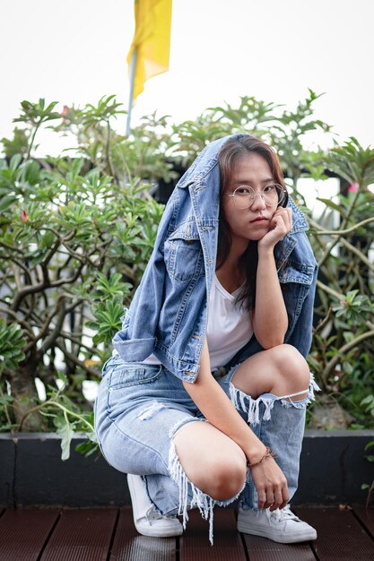 Photo portrait of young woman crouching against plants